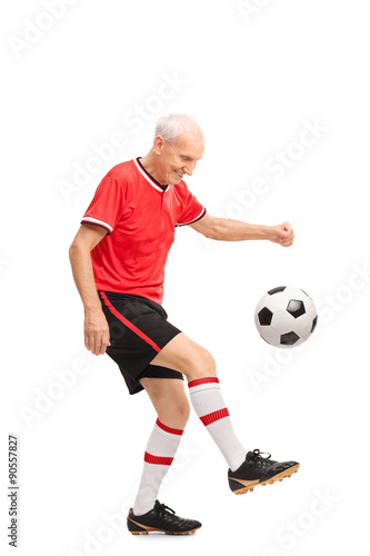 Senior man in a red jersey juggling a football