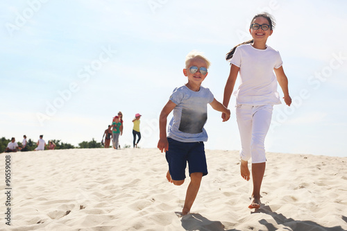 Słoneczne wakacje. Dzieci biegną po plaży photo