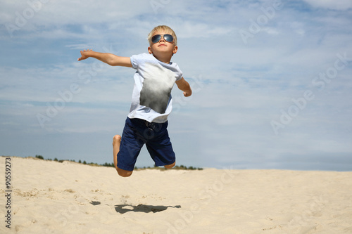 Umiem latać! Chłopiec podskakuje na piaszczystej plaży