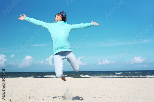 Wakacje! Dziewczynka wysoko podskakuje na piaszczystej plaży