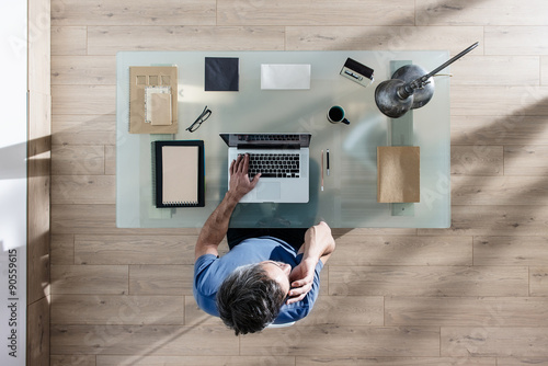 Фотография top view, a man sitting at tidy desk and working on his laptop