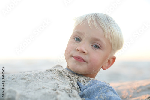 Zabawa w piasku na plaży.Wesoły chłopiec bawi się w piasku na plaży