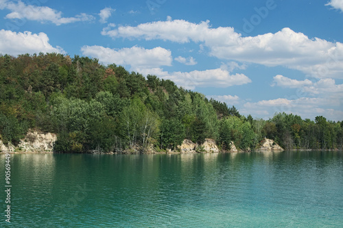 Lake with green water and hill with trees