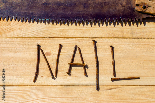 Rusty nails and rusty saw on the wooden table