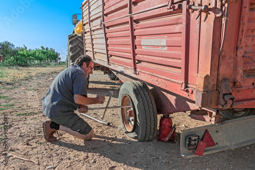 man repair tire of trailer in farm 