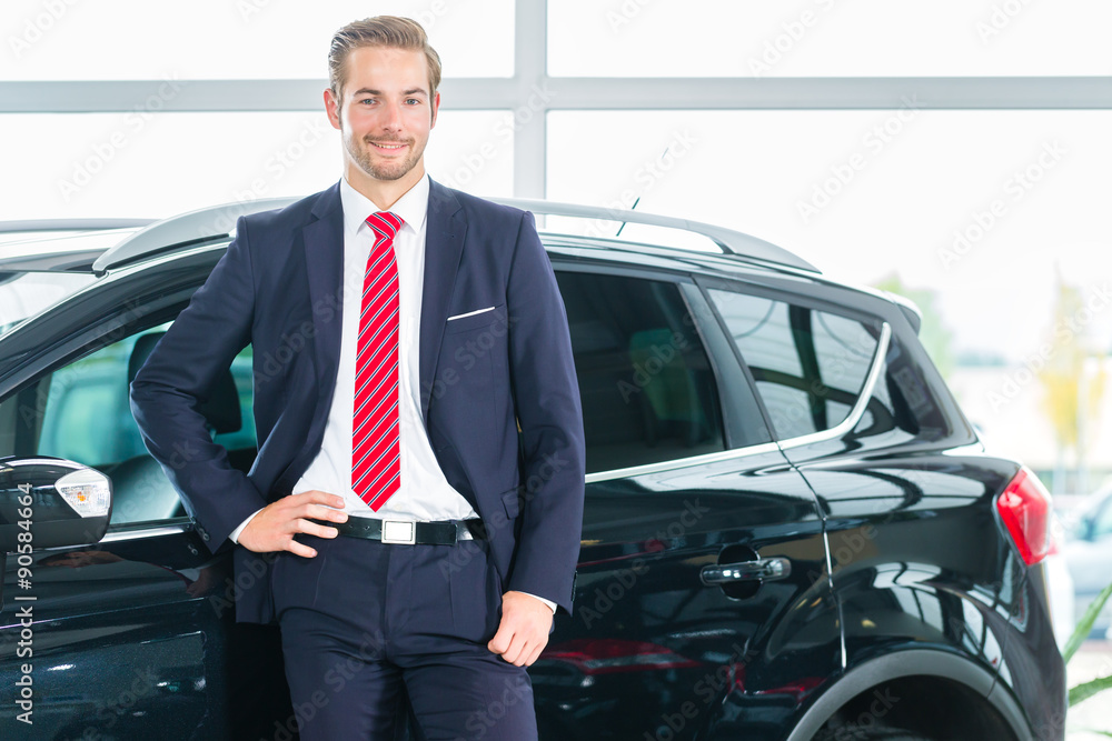 Verkäufer oder Autoverkäufer in einem Autohaus präsentiert seine Autos und Neuwagen im Ausstellungsraum Verkäufer oder Autoverkäufer in einem Autohaus präsentiert seine Autos und Neuwagen im Ausstellungsraum