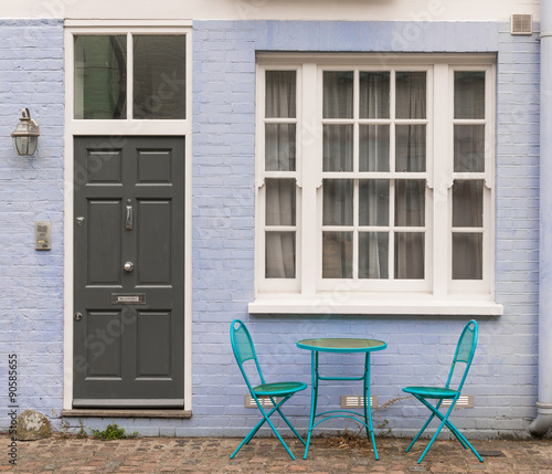 Two blue metal chairs and table next to black door