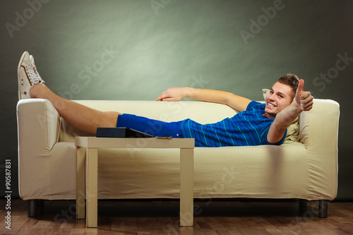 Young man relaxing on couch making thumb up