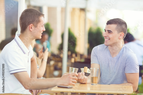 Two young men relaxing in a cafe and drinking beer