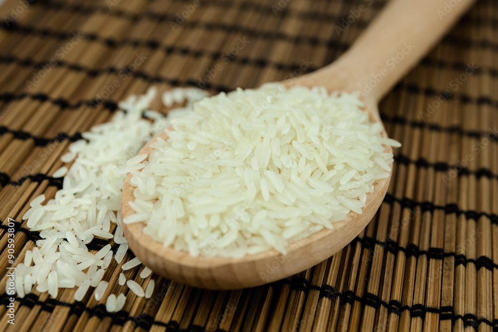 Rice in wooden spoon on traditional Asian plate mat Rice in wooden spoon on traditional Asian plate mat