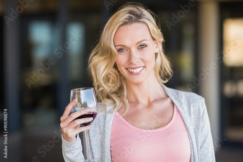 Portrait of smiling blonde woman standing and holding wineglass