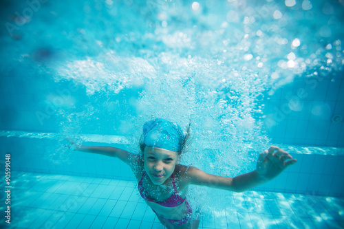 Child swims in pool underwater.