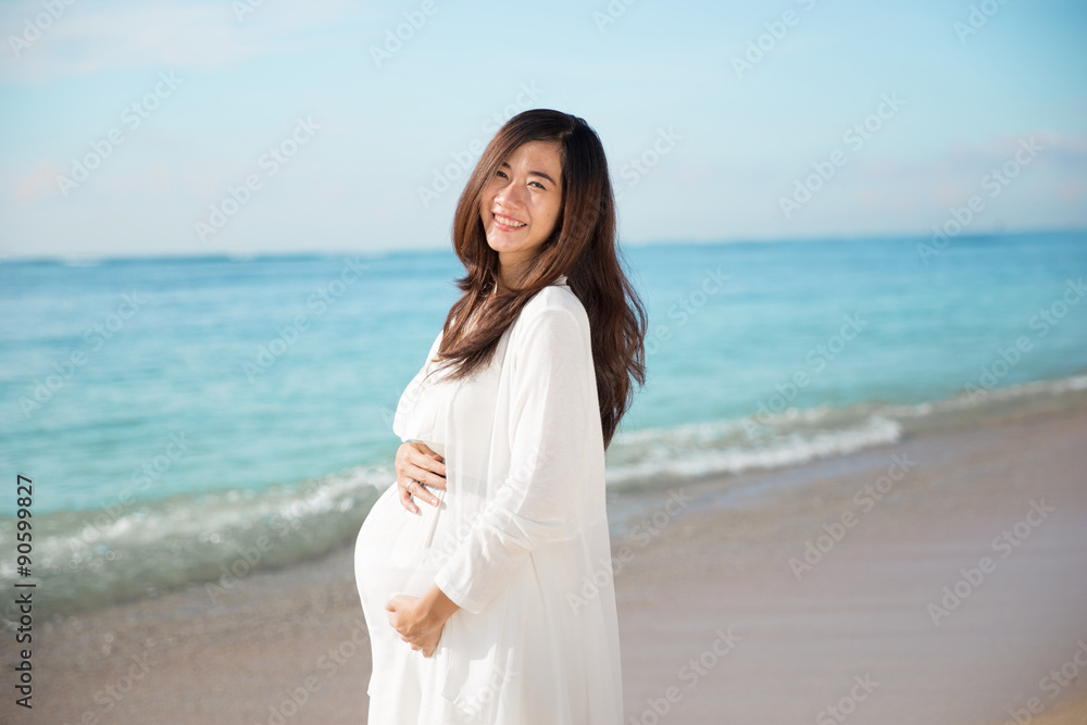 Happy asian pregnant woman smile while touching her tummy on the Happy asian pregnant woman smile while touching her tummy on the