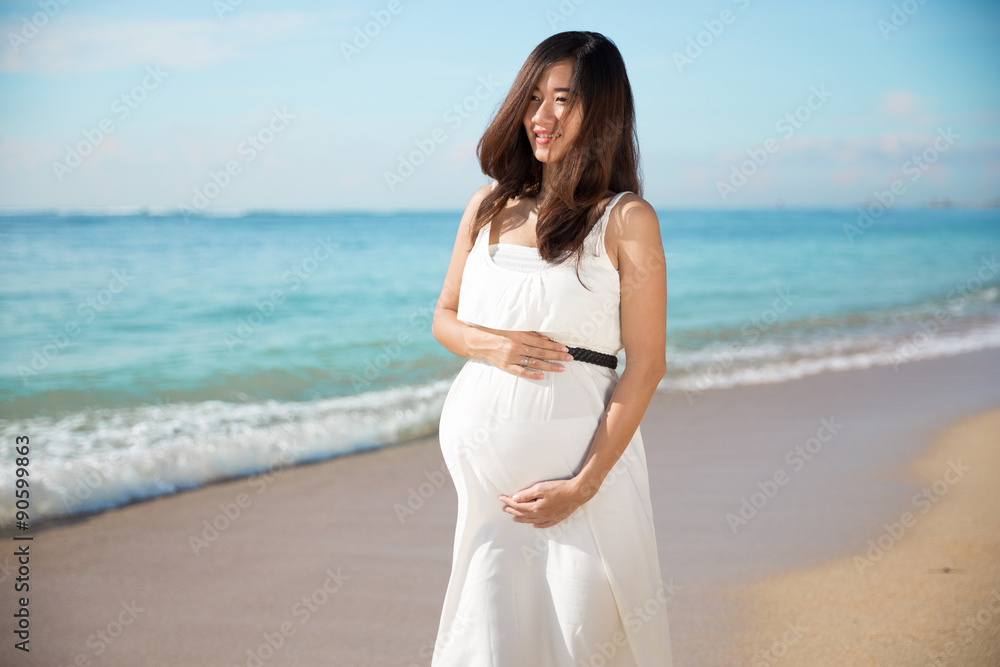 Happy asian pregnant woman smile while touching her tummy on the Happy asian pregnant woman smile while touching her tummy on the