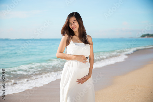 Happy asian pregnant woman smile while touching her tummy on the