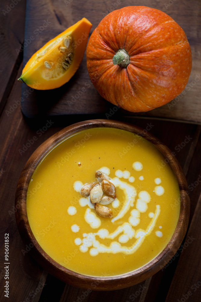 Above view of fresh pumpkin cream-soup in a wooden bowl, closeup Above view of fresh pumpkin cream-soup in a wooden bowl, closeup