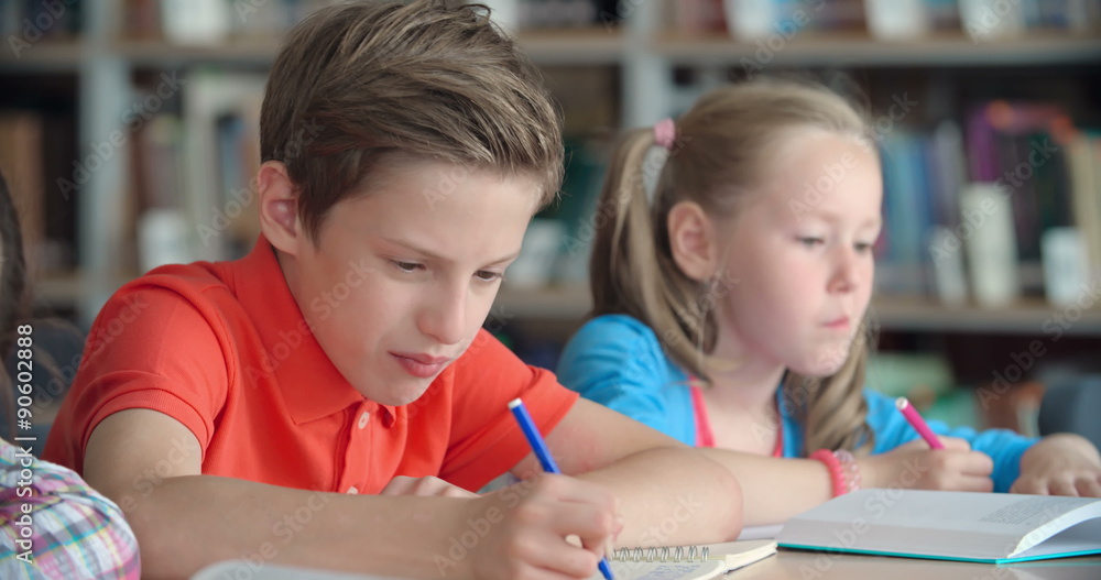 Elementary student finishing task in class, his mate asking for hint Elementary student finishing task in class, his mate asking for hint