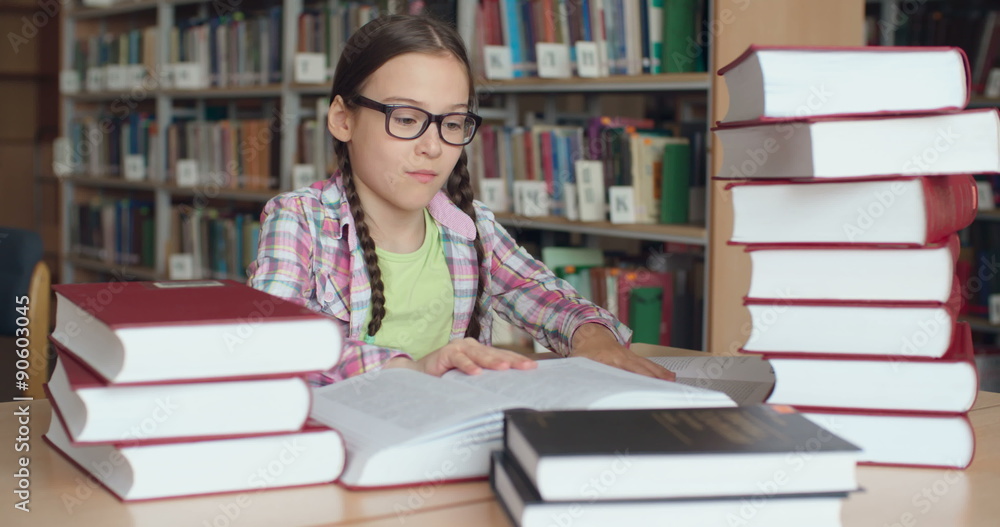 Smart in eyeglasses schoolgirl doing research in library Smart in eyeglasses schoolgirl doing research in library