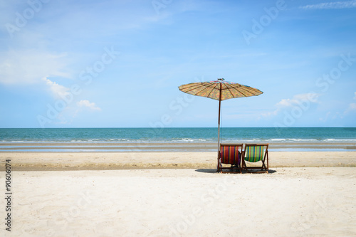 Beach chairs on the sand beach with cloudy blue sky background © nuttawutnuy