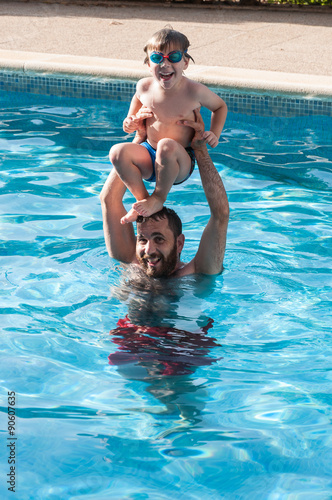 Niño jugando con su padre en la piscina