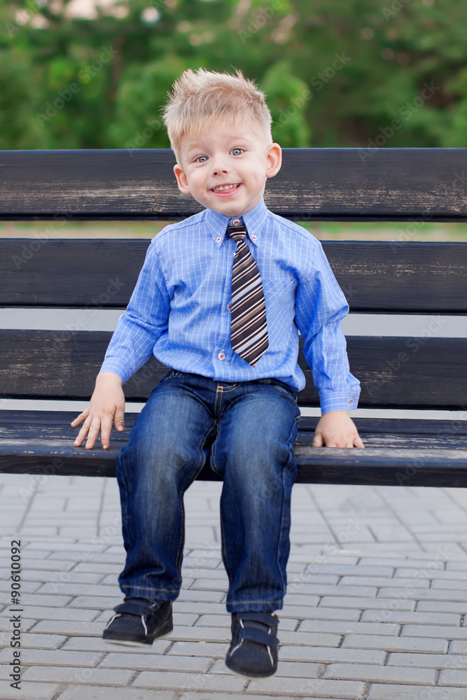 Young boy in the blue shirt, jeans and striped tie is sitting o Stock Photo  | Adobe Stock