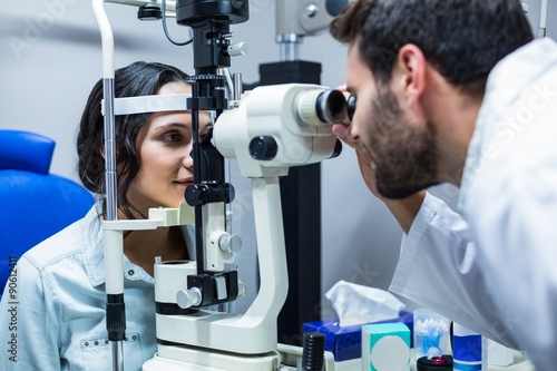  Optician examining womans eyes through slit lamp photo