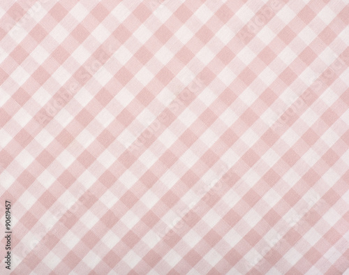 Close up on checkered tablecloth fabric. Pink with white tartan square pattern as background.