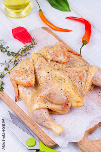 Whole fresh raw chicken prepared for roast with thyme and tomatoes cherry photo