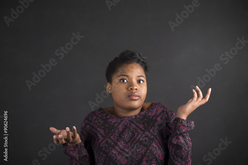 African woman with an I don't know gesture on blackAfrican American woman with an I don't know gesture on blackboard backgroundboard background photo