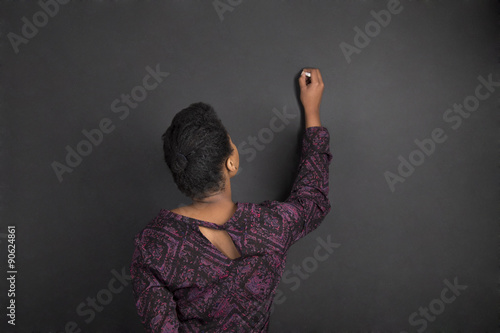 African American woman teacher writing on chalk black board background