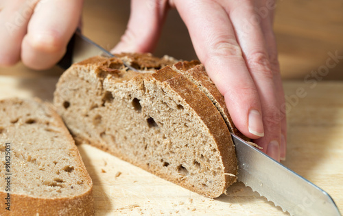 Hands cutting rye bread. Shallow dof.