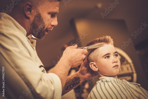 Obraz na plátne Little boy visiting hairstylist in barber shop