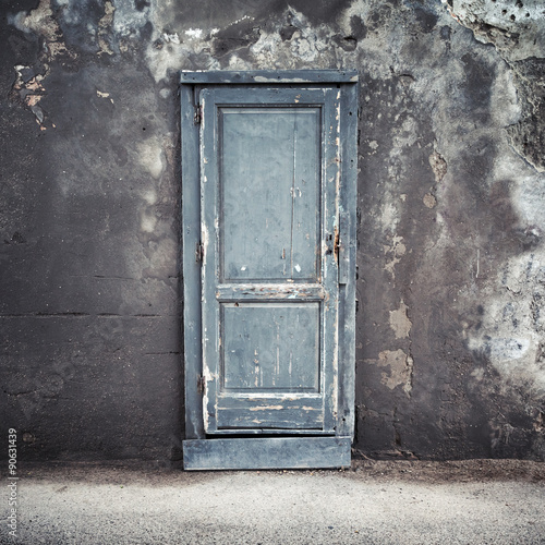 Old blue wooden door in concrete wall © evannovostro