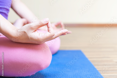 Unrecognizable person meditating and doing yoga exercise indoor