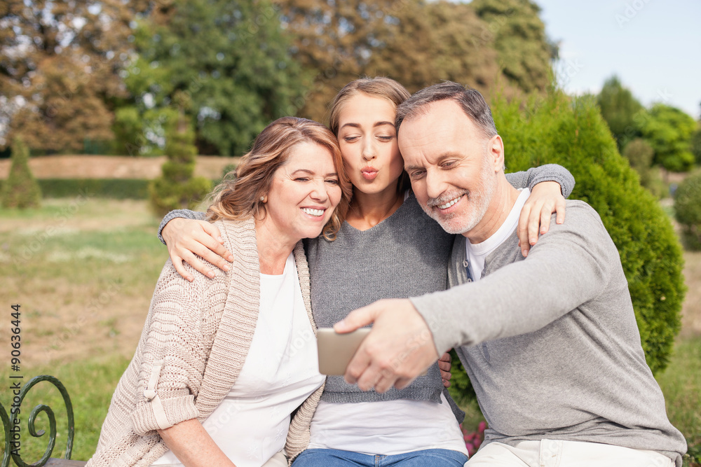 Obraz premium Pretty mature family is photographing themselves in park