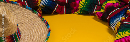 Mexican Sobrero and Serape blanket on yellow background with cop