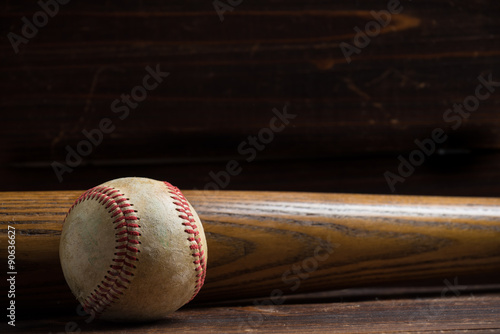 A wooden baseball bat and ball on a wooden background photo