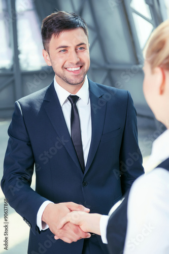 Attractive man in suit receives handshake from his colleague