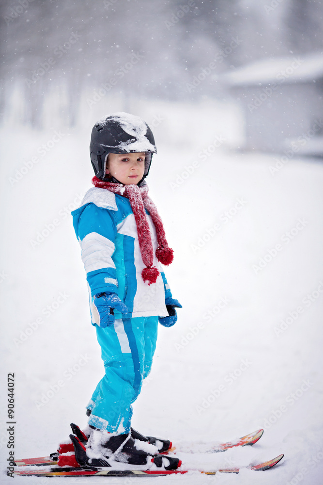 Adorable little boy with blue jacket and a helmet, skiing Adorable little boy with blue jacket and a helmet, skiing