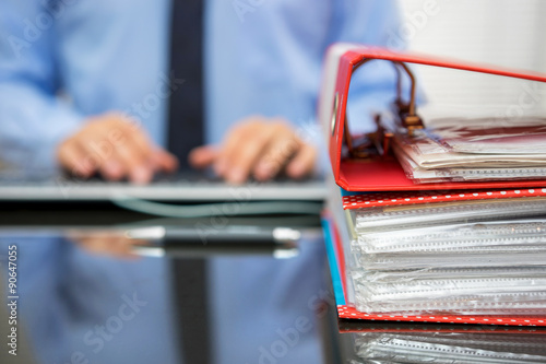 accountant with stack of invoices is inserting data into compute photo