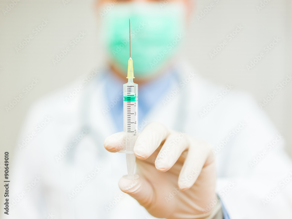 Doctor is holding an injection with needle with focus on injection Doctor is holding an injection with needle with focus on injection