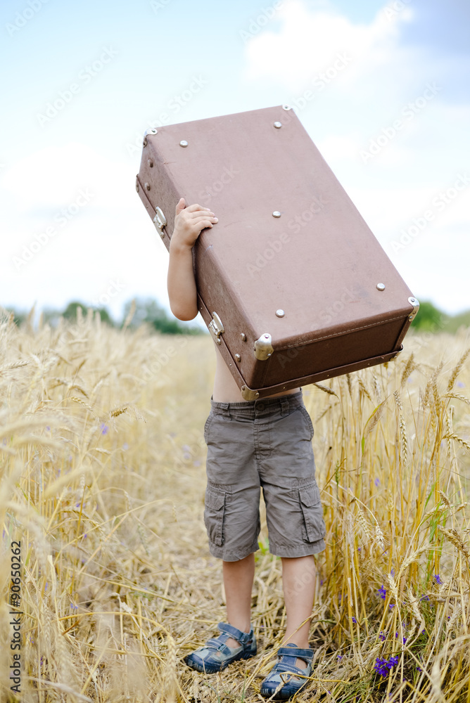 Little boy lifting up big old suitcase in wheat field Stock-foto | Adobe  Stock