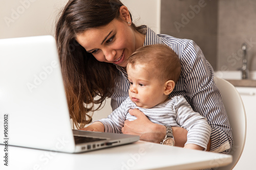 Mother and her baby playing games on internet.