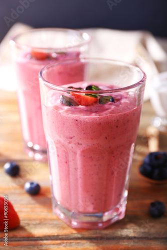 Glasses of berry smoothie on wooden table, closeup