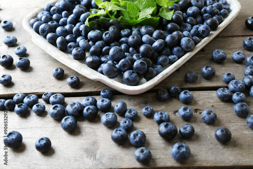 Tasty ripe blueberries with mint on wooden table close up Tasty ripe blueberries with mint on wooden table close up