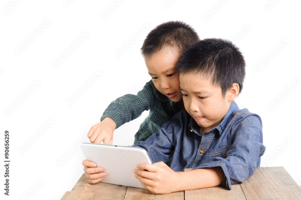 Two Boy sharing tablet device on wood table look happy