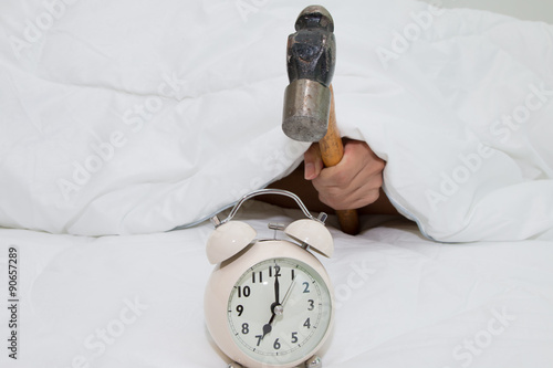 Closeup of a man with a hammer smashing alarm clock