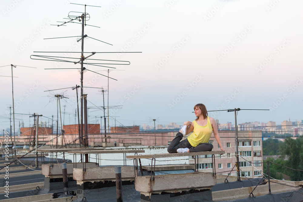 girl doing relaxing yoga exercises on the roof at evening