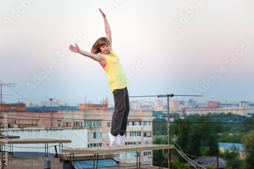 bright girl dancing on tiptoe at sunset on the roof