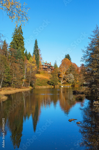 Manor house by the river in autumn landscape